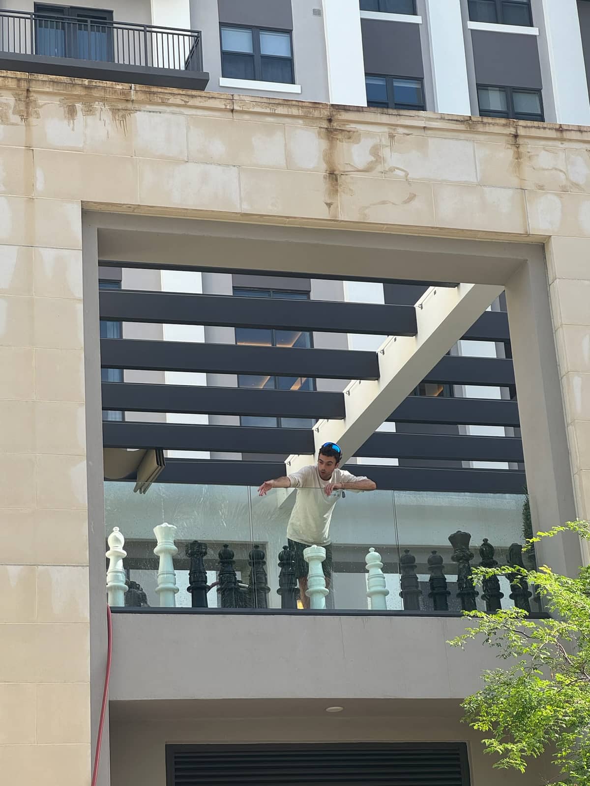Co-founder Eliot De Paz working along the glass railing of an amenity terrace, a stained stone facade above him