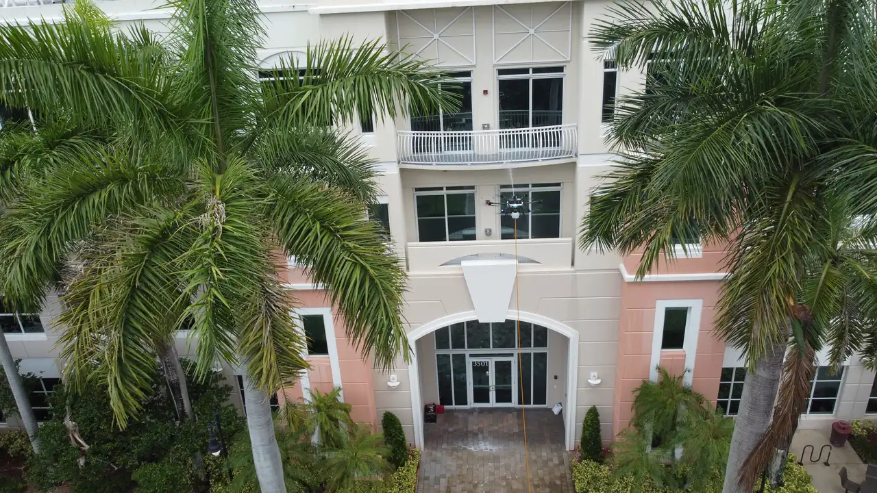 Aerial view of a tethered cleaning drone working a commercial facade, a project delivered in Florida